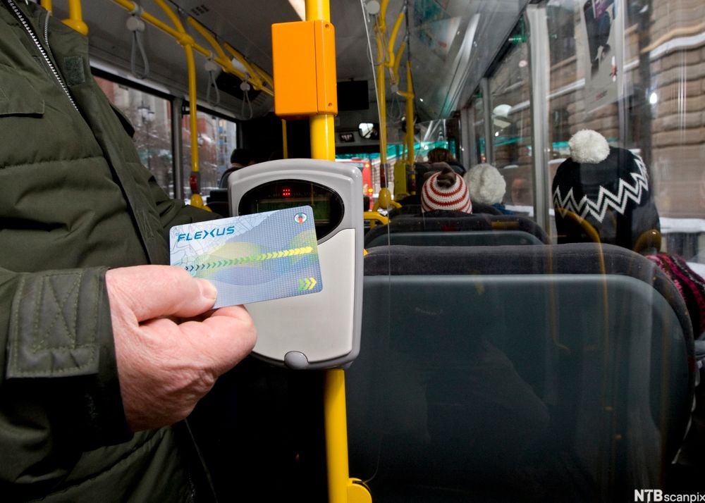 En passasjer betaler elektronisk på bussen. Foto.