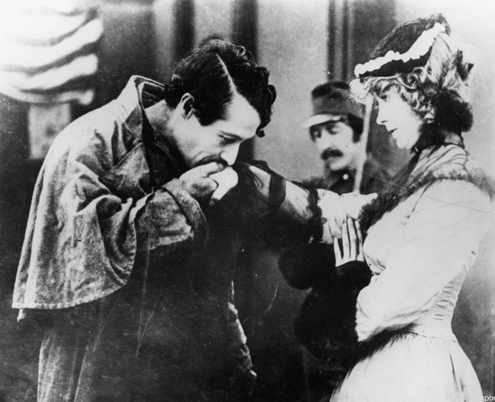 En mann som kysser hånda til en kvinne. Svart-hvitt foto.