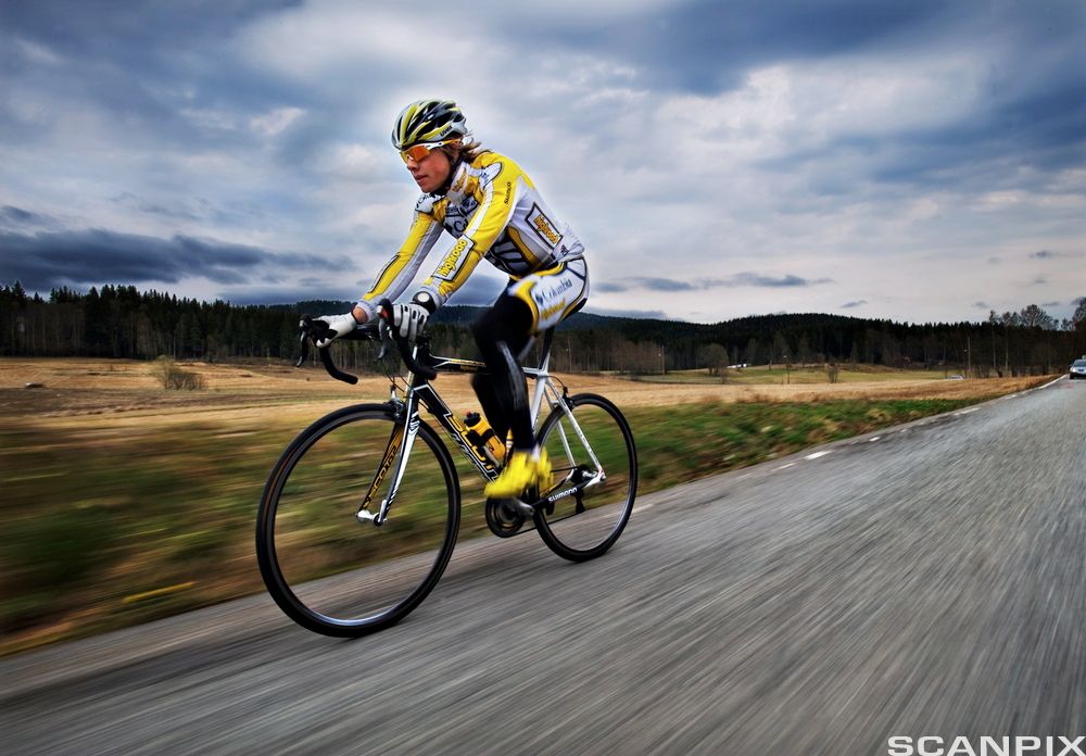 Mann med treningstøy og hjelm på sykkel. Foto.