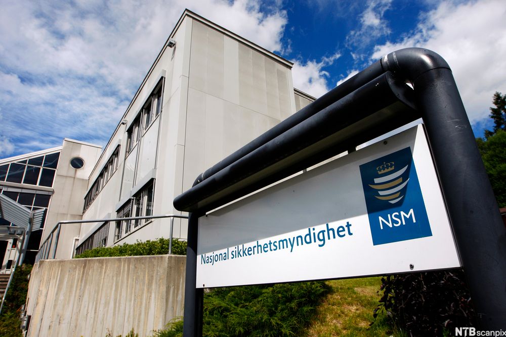 Skilt der det står Nasjonal sikkerhetsmyndighet. Kontorbygning i bakgrunnen. Foto.