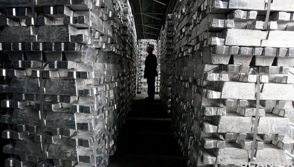 En arbeidstaker går mellom stabler av blokker i ren aluminium. foto.