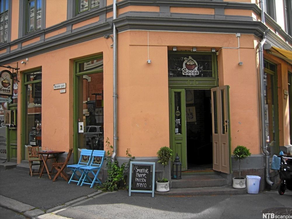 Utsida av ein kafé som heiter Cocos. Bord og stolar står langs fortauskanten. Foto.