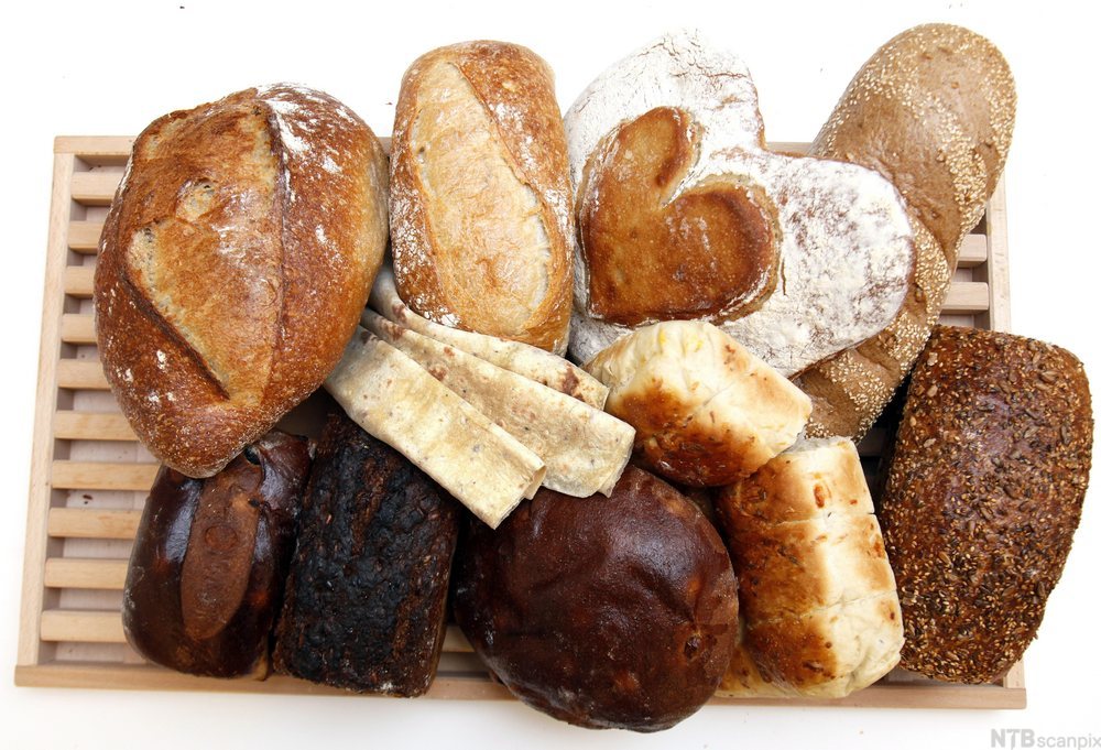 Diverse brød og rundstykker på ei skjærefjøl. Foto.