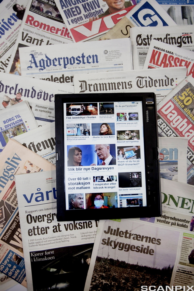 Nettbrett med nettavis på skjermen ligger oppå flere papiraviser. Foto.
