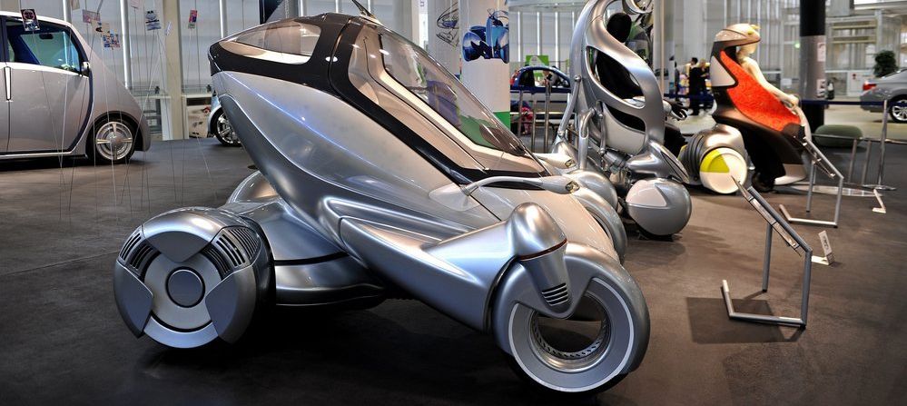 Ulike framtidsrettede framkomstmidler og biler utstilt i en hall. Foto.