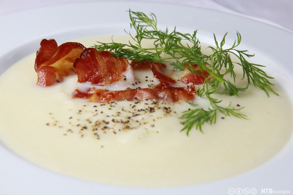 Kremfarget suppe med flere fargerike råvarer som bryter overflaten. Foto.