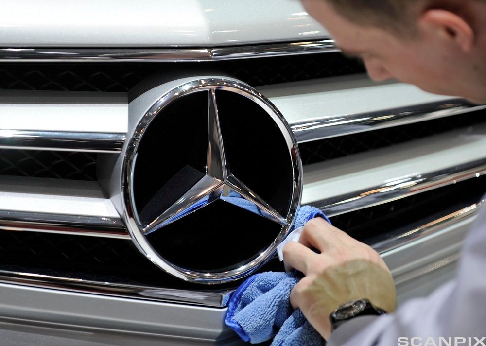En mann polerer Mercedes-stjernen på en bil. Foto.