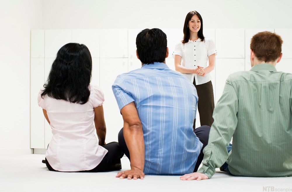 Leder snakker til tre ansatte som vi kun ser ryggen til. Foto.