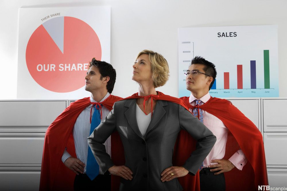 Tre selgere med røde kapper på seg og salgsplansjer i bakgrunnen. Foto.