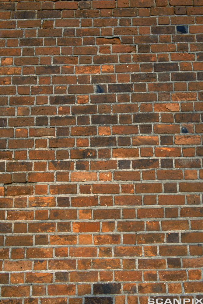 Ein vegg som er mura med raud teglstein. Foto.