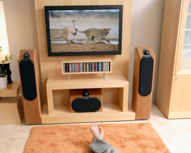 To bein på et teppe foran en tv med høyttalere under og på sidene. Foto.