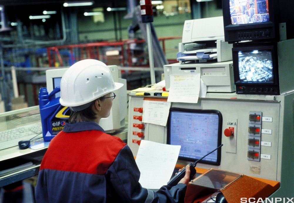 Operatør i kontrollrom som overvåker produksjonslinje. Foto.