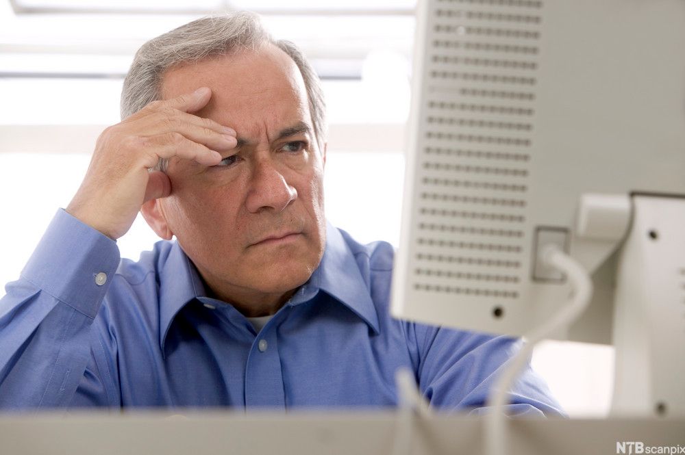 Forvirret mann ved datamaskin. Foto.