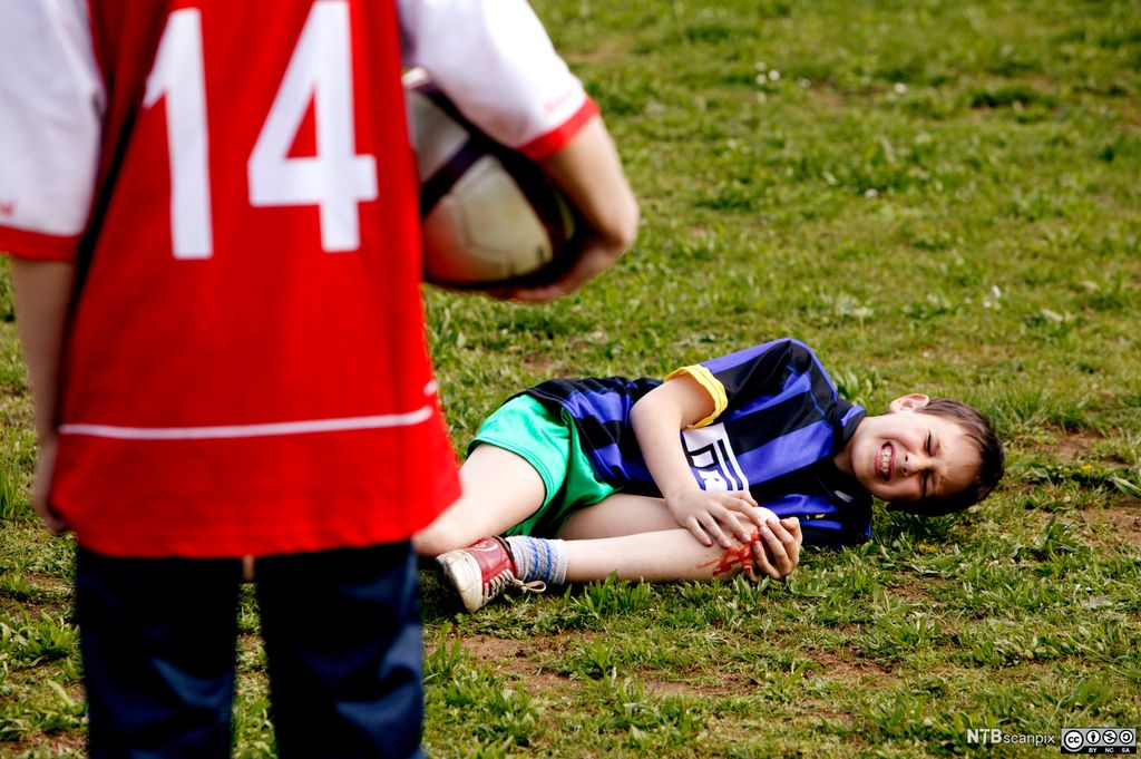 Gut ligg med skada kne på fotballbanen. Foto.