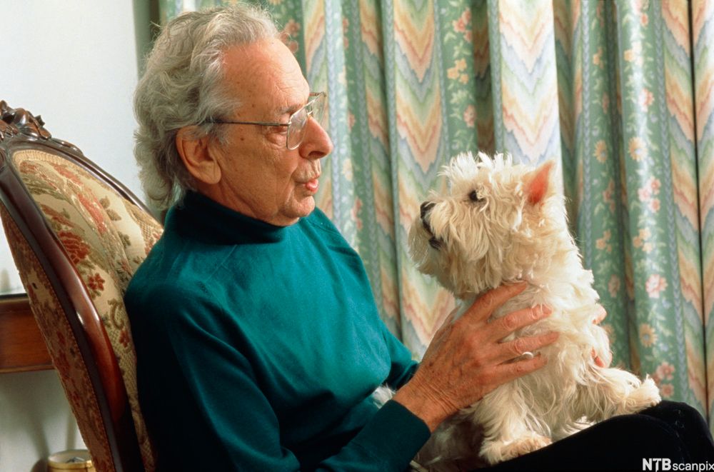 Eldre mann med hund på fanget. Foto.