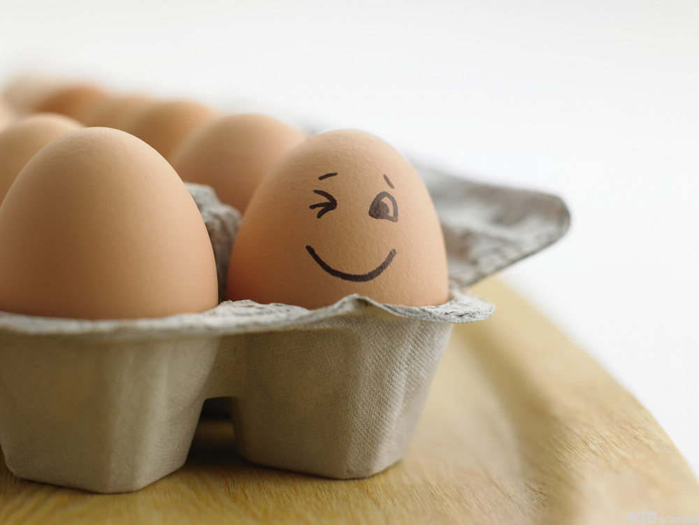 Eggekartong med brune egg. Ett av eggene har et påtegnet smilefjes. Foto.