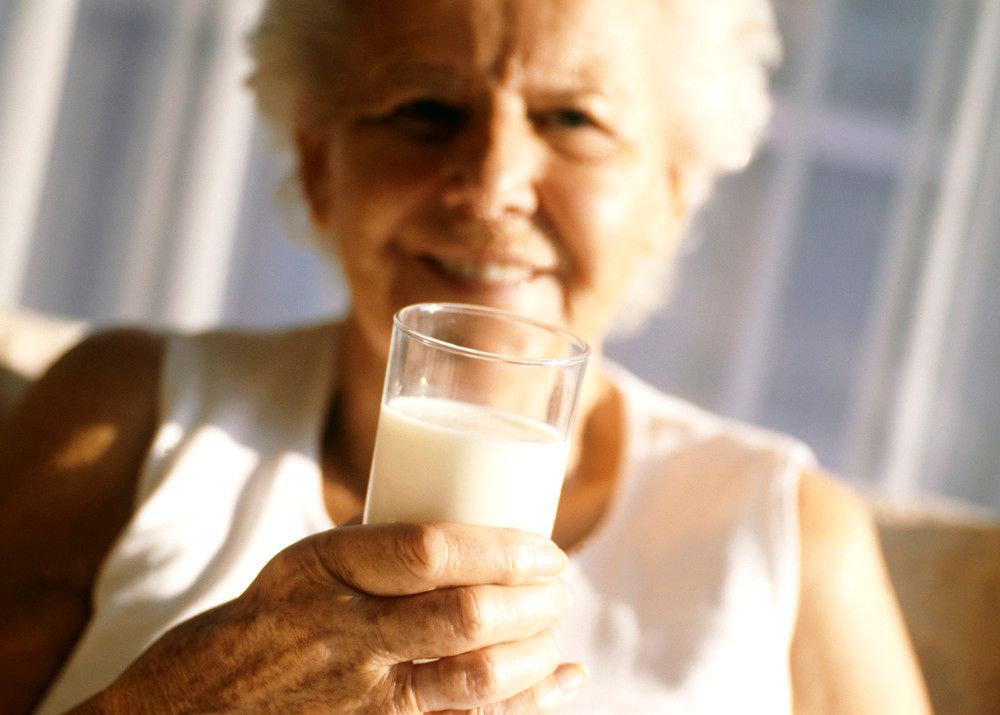 Eldre kvinne drikker melk. Foto.