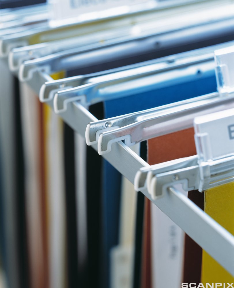 Fysiske arkivmapper i ulike farger på rekke og rad i et arkivskap. Foto.