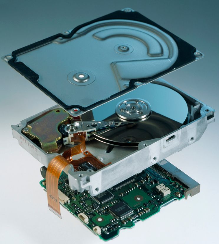 Harddisk som er åpnet opp, viser magnetplatene, lesehode og lesearm inni, og kretskortet som styrer harddisken, er plassert på undersiden av harddiskens kabinett. Foto.