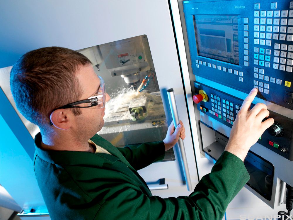 Metallarbeider opererer ei CNC-fresemaskin. Foto.