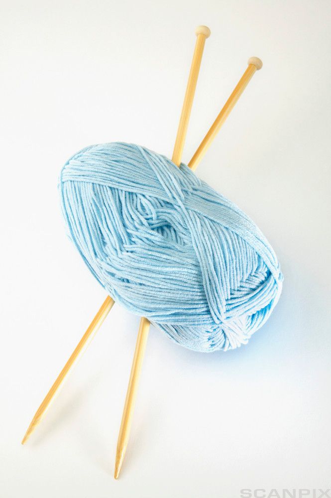Lyseblått garnnøste og strikkepinner. Foto.