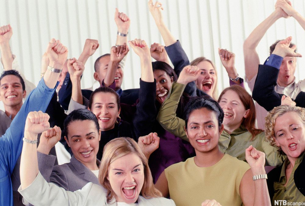 En gruppe engasjerte og entusiastiske mennesker jubler med hendene i luften. Foto.