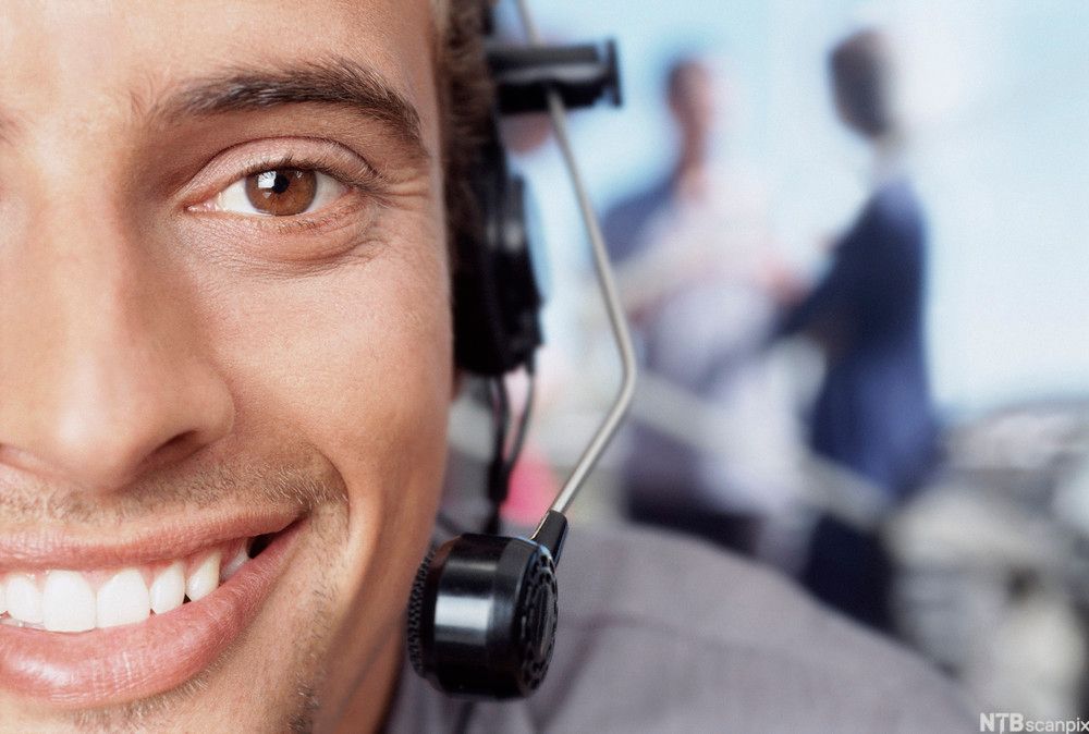 Utsnitt av ansiktet til en mann med hodemikrofon. Foto.