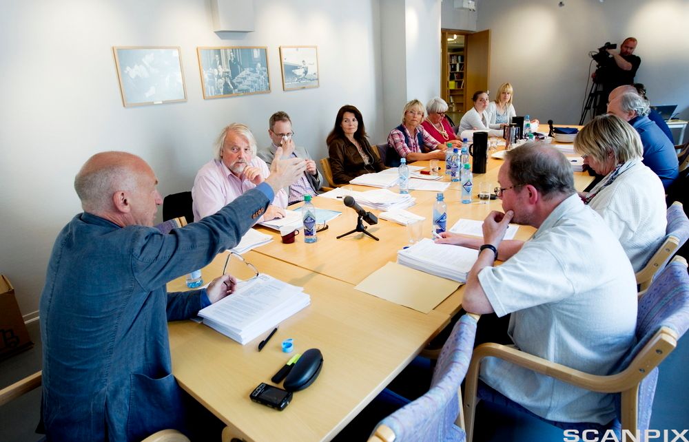 Menn og kvinner sitter rundt et møtebord. Foto.