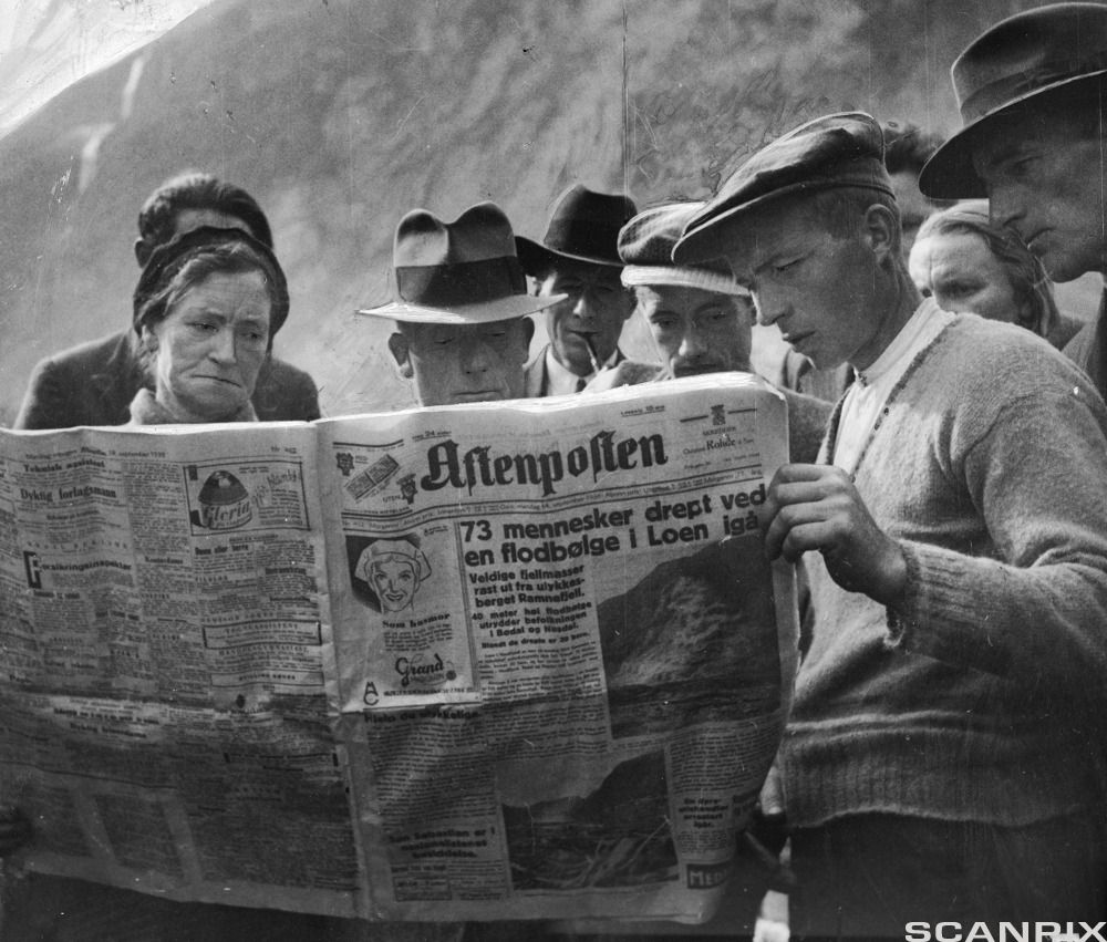 En gruppe mennesker leser om rasulykken i Aftenposten. Foto.