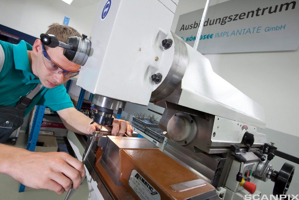 Ung mann med vernebriller opererer fresemaskin. Foto.