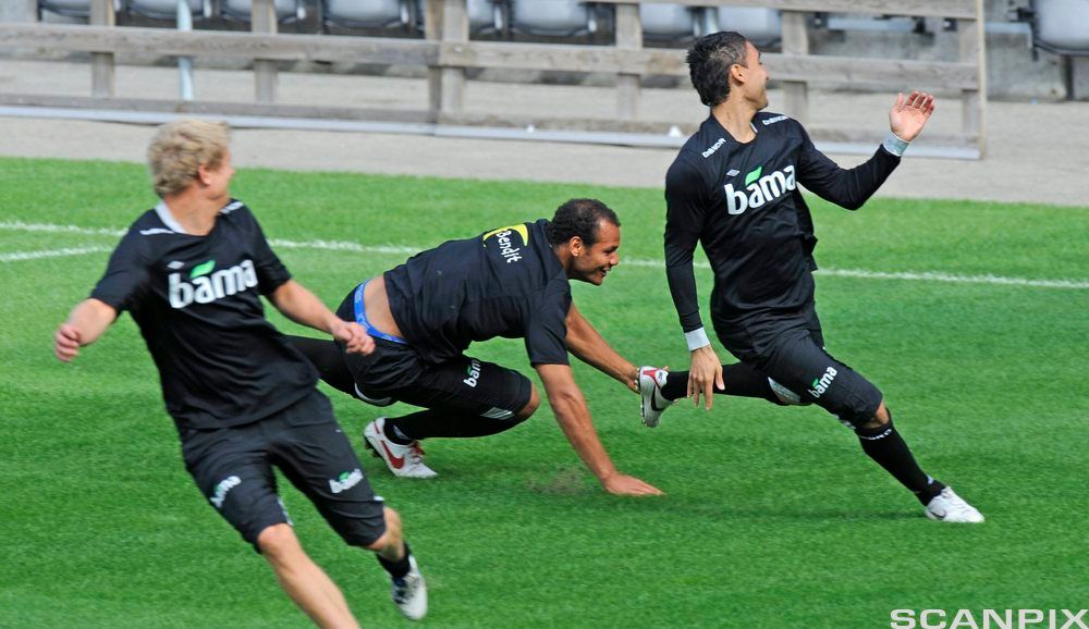 Tre personer løper på en fotballbane. Foto.