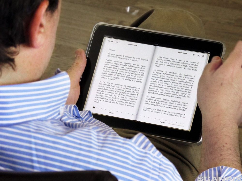 Gutt som leser på nettbrett. Foto. 