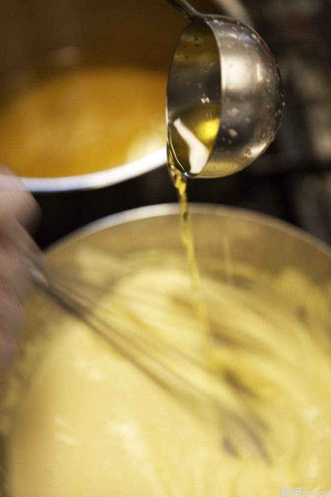 Hollandés i en bolle spes med klaret smør fra ei øse. Foto.