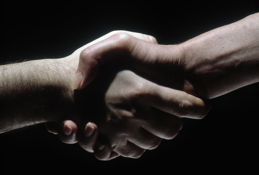 A white and a black hand shaking hands. Photo. 