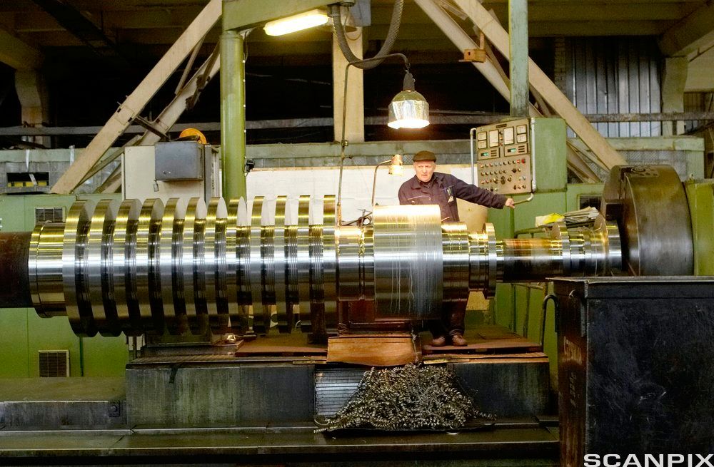 En mann står bak en stor dreiemaskin. Foto. 