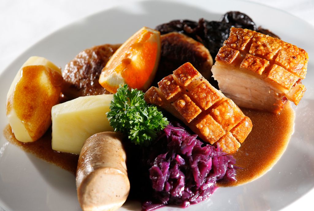 En tallerken med ribbe, potet, rødkål, medisterpølse og brun saus. Foto.