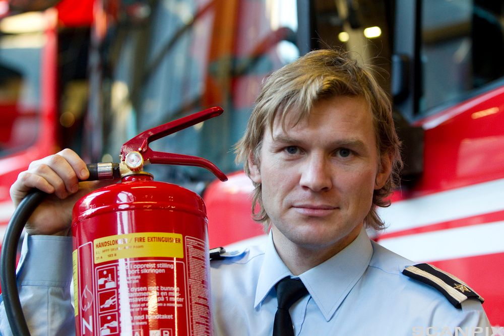 Ein sjåfør viser fram eit brannsløkkingsapparat. Foto.