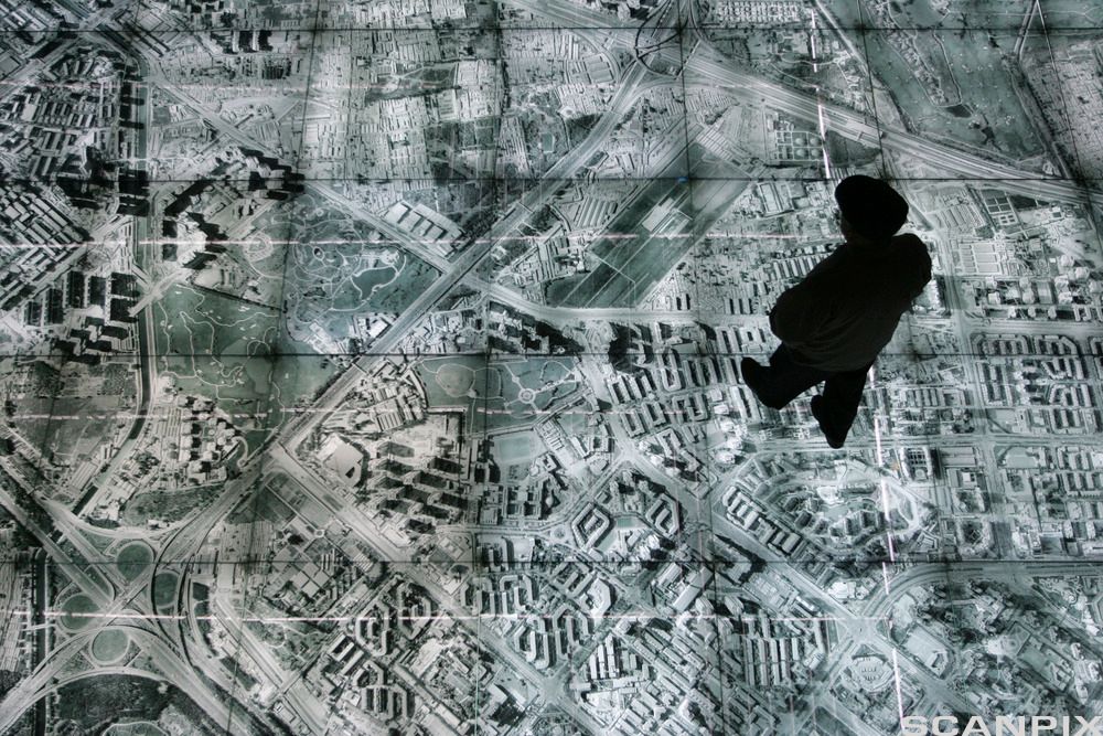 Ein mann trår på noko som liknar eit kart over ein by. Foto. 