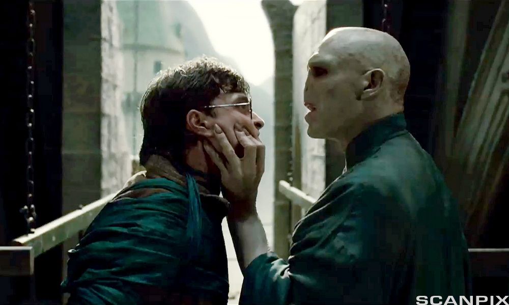 Voldemort grip rundt ansiktet til Harry Potter og ser trugande på han i ei scene frå spelefilmen Harry Potter. Foto.