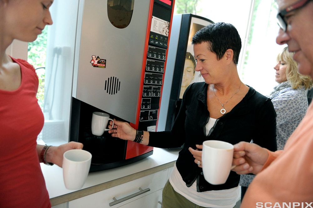 En gjeng kolleger er samlet rundt en kaffemaskin.