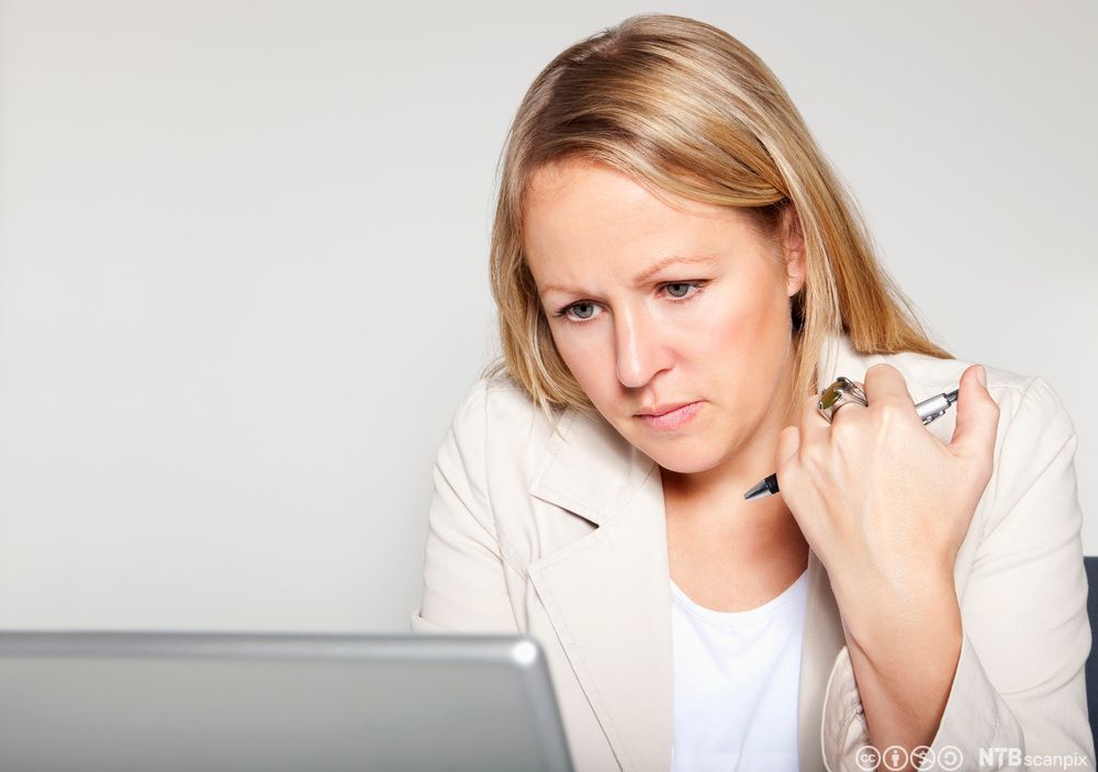 Kvinne sitter ved datamaskinen. Foto.