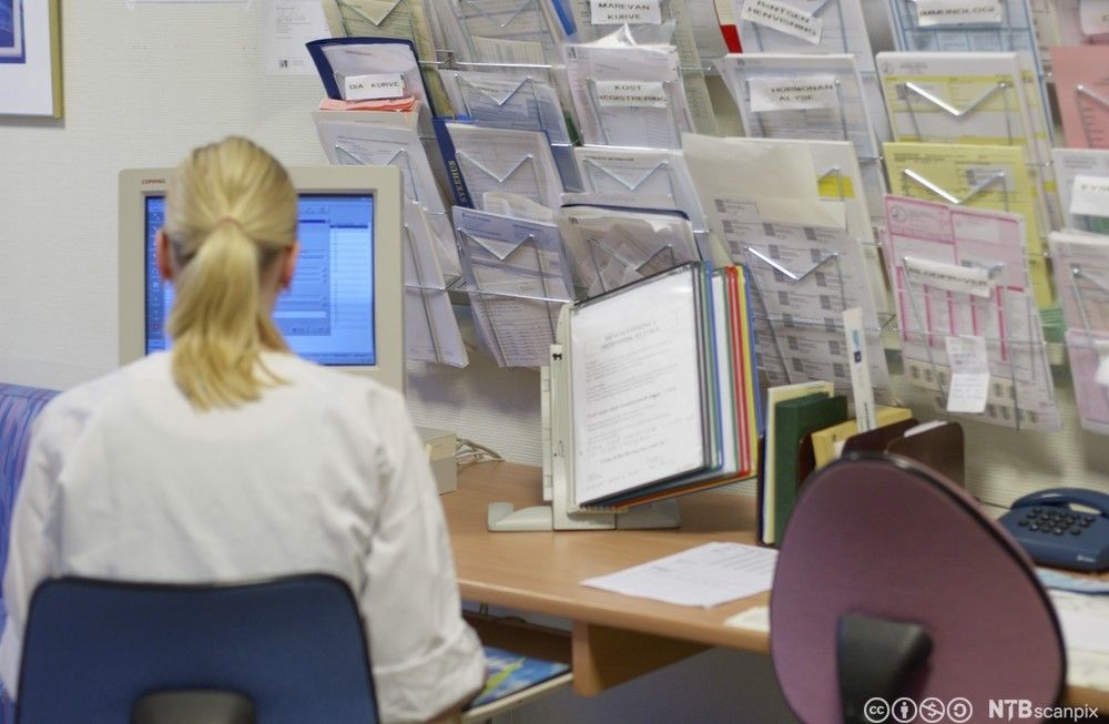 Sykepleier ajourfører pasientjournal på pc. Foto.