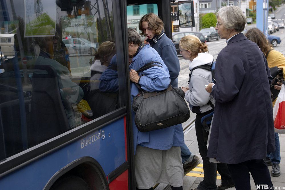 Folk går om bord på bussen på ein busshaldeplass. Foto.