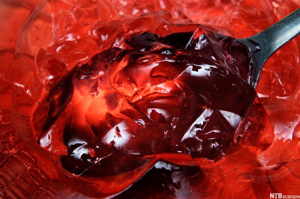 En spiseskje i rød gelé. Foto.