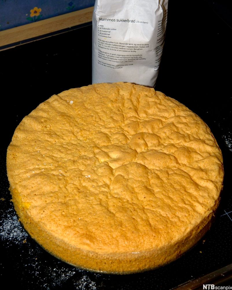 Et sukkerbrød uten noe pynt foran en sukkerpose med en oppskrift på sukkerbrød, "Mammas sukkerbrød". Foto.