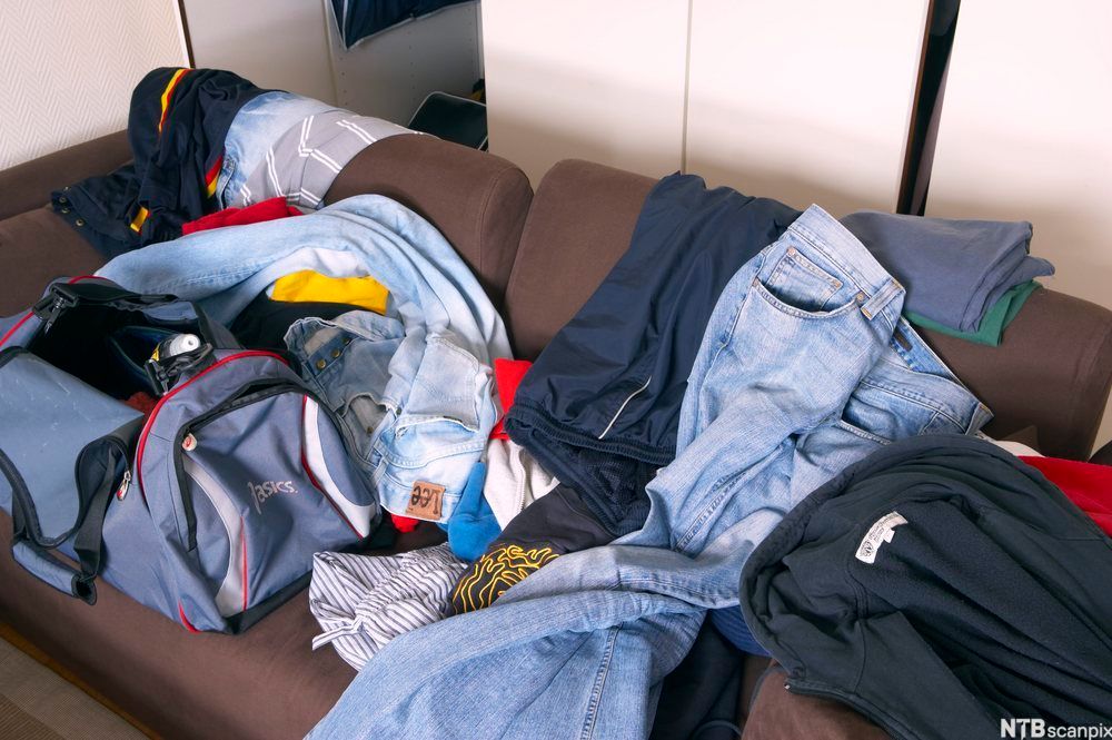 Rotete rom med klær hulter til bulter på en sofa. Foto.