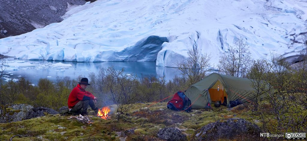 Fjellvandrer tenner bål utenfor teltet ved Briksdalsbreen. Foto.