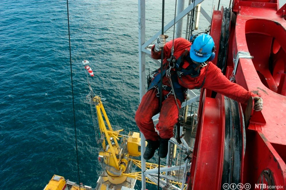 En boredekksarbeider jobber i toppen av RamRig-en, boretårnet. Han bruker ridebelte til å sikre seg med. Foto.