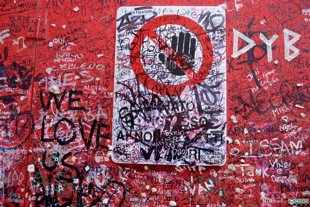 Rød vegg med hvit og svart tagging. Foto.