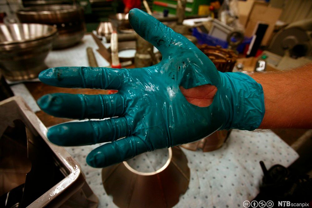 Nærbilde av ei hånd med beskyttelseshanske som er revet opp i håndflata. Foto.